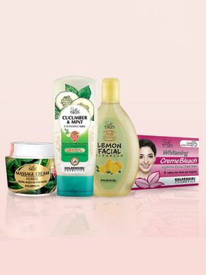 Collection of skincare products including a massage cream, cleansing milk, lemon facial shampoo, and a box of cream bleach on a light pink background.